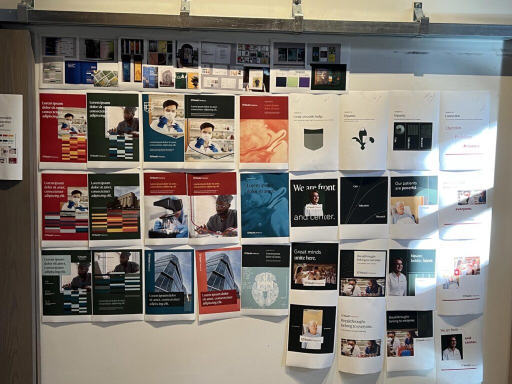 Print-outs of early explorations of the new WashU Medicine brand identity hang on a white board in the Atomicdust office